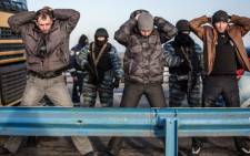 Men hold their hands up on their heads as they are searched by pro-Russian servicemen at Chongar checkpoint blocking the entrance to Crimea on 10 March 2014. Picture: AFP.