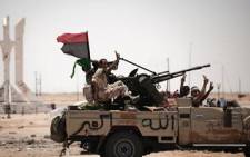 FILE: Libyan rebel fighters flash the victory sign as they drive on 11 June 2011 in Ajdabiya. Picture: AFP