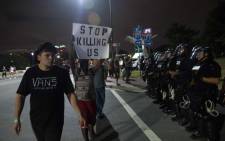 Protesters walk past riot police blocking off a ramp to a highway during a demonstration against police brutality in Charlotte, North Carolina, on 22 September 2016. Picture: AFP.