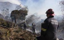 Firefighting teams dampen smouldering vegetation, finally getting a fierce forest fire under control on the foothills of Table Mountain in Cape Town on 19 April 2021. Picture: Rodger Bosch/AFP