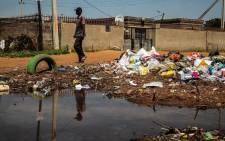 FILE: A man walks past a dumpsite in Ebumnandini on the West Rand, which residents complain is a health risk because they don’t have dustbins. Picture: Kayleen Morgan/Eyewitness News
