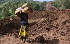A woman carries a rolled-up mattress at a landslide site in Shisakali village of Bududa district, eastern Uganda, on 6 June 2019. Picture: AFP