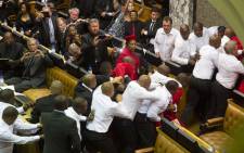 MPs look on as members of the EFF, wearing red uniforms, clash with security forces during South African President's State of the Nation address in Cape Town on 12 February, 2015.