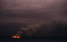 This handout photo taken on 6 January 2020 and received on 7 January from the Australian Department of Defence shows a fire in the distance seen from the Royal Australian Navy's HMAS Adelaide ship off the coast in Eden in New South Wales, as part of bushfire relief operations. Picture: AFP