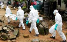 Liberian nurses carry the body of a suspected victim of Ebola at the Sonuwein community in Monrovia, Liberia, 3 October 2014. Picture: EPA/Ahmed Jallanzo.