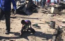 A young boy lends a hand as Overcome Heights informal settlement residents start cleaning up following a fire that gutted about 500 shacks. Picture: Lauren Isaacs/EWN
