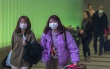 FILE: Travelers arrive at LAX Tom Bradley International Terminal wearing medical masks for protection against the novel coronavirus outbreak on 2 February 2020 in Los Angeles, California. Picture: AFP