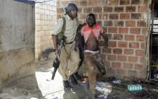 A Zambian Policeman apprehends an alleged looter in the Zingalume Compound where residents have attacked broken and looted foreign-run shops in Lusaka on 18 April, 2016. Picture: AFP.
