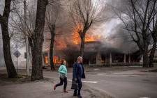 Residents run near a burning house following a shelling Severodonetsk, Donbass region, on 6 April 2022, as Ukraine tells residents in the country's east to evacuate "now" or "risk death" ahead of a feared Russian onslaught on the Donbas region.
