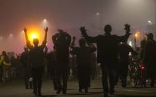 Protesters walk thorugh fog in East Oakland with their hands raised on the second night of demonstrations following a Staten Island, New York grand jurys decision not to indict a police officer in the chokehold death of Eric Garner on 4 December, 2014 in Oakland. Picture: AFP.