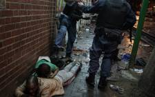 Police make people lie on their stomachs after finding them looting inside a store in Hillbrow. Picture: Boikhutso Ntsoko/ Eyewitness News.
