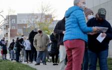 An election official (3rd R) confirms voter information as voters wait in line to cast their ballots on the final day of early voting for the 2020 presidential election on 2 November 2020 in Cedar Rapids, Iowa. Picture: AFP.