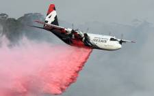 This file photo taken on January 10, 2020 shows a C-130 Hercules plane from the New South Wales Rural Fire Service dropping fire retardent to protect a property during an operation to douse bushfires in Penrose, in Australia's New South Wales state. Picture: AFP