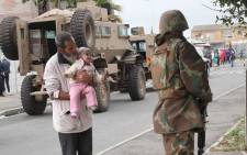 A grandfather holds his baby up to greet a soldier as SAPS and members of the SANDF conduct crime-fighting operations in Manenberg. Picture: Bertram Malgas/EWN