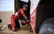 FILE: Toyota's driver Giniel De Villiers of South Africa kneels next to his car after stopping due to technical problems during Stage 3 of the Dakar 2019. Picture: AFP