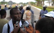 Ferdinand Ayite, president of the SOS -Journalist in Danger speaks to the press as behind security forces stand to prevent a crowd of several hundred journalists and members of the public from protesting in front of the Palais des Congres in Lome on February 19, 2013. Picture: AFP Photo / Daniel Hayduk. 