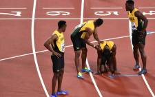 Jamaica's Usain Bolt (2R) reacts after injuring himself as team-mates try to help him during the final of the men's 4x100m relay athletics event at the 2017 IAAF World Championships at the London Stadium in London on 12 August 2017. Picture: AFP.