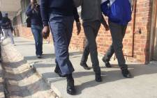 A police officer walks with two students at the Fezeka Secondary School during a search and seizure operation on 12 May 2016. Picture: Siyabonga Sesant/EWN.