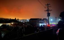 FILE: This handout photo received courtesy of Caitlin Nobes and taken on 31 December 2019 shows the darkened sky glowing orange from bushfires many kilometres away in Bermagui, Australia. Picture: AFP