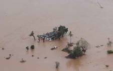 FILE: This handout picture taken and released on 18 March 2019 by the Mission Aviation Fellowship shows people on a roof surrounded by flooding in an area affected by Cyclone Idai in Beira. Picture: AFP