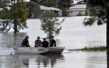 This picture taken on 2 March 2022, shows residents steering their boat through a flooded street in Lawrence, some 70 kms from the New South Wales town of Lismore. Picture: SAEED KHAN/AFP