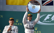FILE: Mercedes AMG Petronas F1 Team's British driver Lewis Hamilton (C) holds the trophy aloft after winning the Formula One Australian Grand Prix as teammate German Nico Rosberg (L) looks on in Melbourne on 15 March  2015. Picture: William West/AFP 