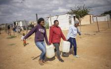 FILE: Three women carry jars filled with water from a tank in an informal settlement in Hammanskraal on 23 May 2023, amid a deadly cholera outbreak. City officials urged residents of Hammanskraal and surrounding areas not to drink from the tap, adding water tankers were being supplied. Picture: Michele Spatari/AFP