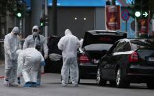 Forensic experts of the police search for evidence in and around the car of Greek former prime minister Lucas Papademos in Athens on May 25, 2017, after Papademos was hurt when an explosive device went off inside his car. Picture: AFP.