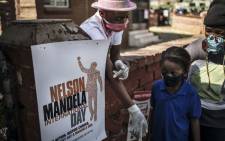 FILE: A young volunteer from the grassroots charity Hunger has no Religion tries to have children queuing to receive food respecting social distancing during a special Mandela Day service in Johannesburg, on 18 July 2020. Picture: MARCO LONGARI/AFP
