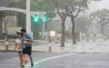 A couple crosses the street in the city centre of Naha, Okinawa prefecture, on 29 September 2018 as typhoon Trami is actually hitting Japan. Picture: AFP