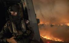 FILE: This handout photo taken on 21 December 2019 and obtained on 22 December from the Australia Department of Defence shows an aircrewman monitoring the Tianjara fire from a helicopter in the Moreton and Jerrawangala National Park in Moreton. Picture: AFP