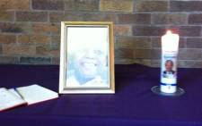 A white candle burns in honour of Madiba at the Regina Mundi Church, alongside a photograph and a condolence book. Picture: Chanel September/EWN.