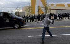 A man throws a wood board at police on April 27, 2015 in Baltimore, Maryland. Violent street clashes erupted in Baltimore after friends and family gathered for the funeral of Freddie Gray, a 25-year-old black man whose death in custody triggered a fresh wave of protests over US police tactics. Picture: AFP.
