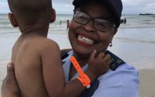 An SAPS officer with a tagged child at Mnandi Beach in Cape Town on 26 December 2018. Picture: Kaylynn Palm/EWN