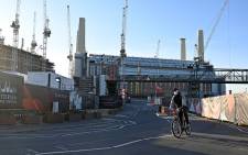 A man, wearing a face mask as a precautionary measure against COVID-19, cycles past the Battersea Power Station development in south London on 24 March 2020, as Britain's Chancellor of the Duchy of Lancaster, Michael Gove clarified that major construction work should go ahead despite the lockdown due to the novel coronavirus. Picture: AFP