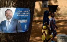 Children walk past a campaign poster of for the presidential candidate of the ruling Union for the Republic (UNIR) party President Faure Gnassingbe in Mango, northern Togo, on 15 February 2020. Picture: AFP
