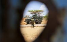 FILE: A Kenyan soldier serving with the AMISOM is pictured through a bullet hole in the gate of the compound housing the former offices of the UN’s refugee agency in Kismayo, southern Somalia. Picture: UN Photo.