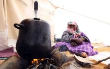 A displaced woman from the Libyan town of Tawergha, 260km east of the Libyan capital Tripoli, prepares food on 8 February 2018 at a temporary camp, 20kms from Tawergha, after they were denied entry to their hometown. Picture: AFP.