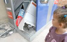 A young girl looks at the remains of an ATM in Lenasia, after robbers bombed it. Picture: SAPA.