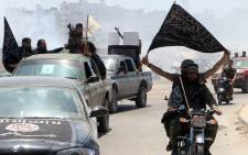 Fighters from Al-Qaeda’s Syrian affiliate Al-Nusra Front drive in the northern Syrian city of Aleppo flying Islamist flags as they head to a frontline, on 26 May 26 2015. Picture: AFP/AMC/Fadi Al-Halabi.