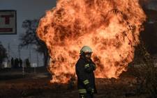 A Ukrainian firefighter stands next to flames rising from a fire following artillery fire on Kharkiv on 25 March 2022. 