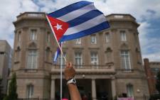 FILE: A supporter waves a Cuban flag in front of the country’s embassy after it re-opened for the first time in 54 years 20 July, 2015 in Washington, DC. Picture: AFP.