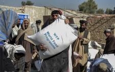 FILE: In this file photo taken on 19 October 2021 Afghans carry sacks of grains distributed as aid by the World Food Programme in Kandahar, Afghanistan. Picture: Javed Tanveer / AFP.
