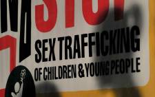 FILE: Children are silhouetted in front of posters displayed during a prayer for Justice and Protection against Sex Trafficking of Children and Young People. Picture: AFP