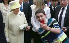 A boy takes a selfie with Queen Elizabeth II during a visit to Belfast, Northern Ireland. Picture: AFP.