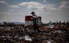 A waste picker walks through tons of trash, looking for recyclables.