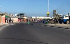 The crowd quickly disperses between shacks as protesters respond to approaching police in Montague Gardens by throwing stones. Picture: Natalie Malgas/EWN.