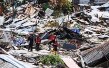Rescuers walk past debris at Perumnas Balaroa village in Palu, Indonesia's Central Sulawesi on 5 October 2018, following the 28 September earthquake and tsunami. Picture: AFP