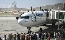 FILE: Afghan people climb atop a plane as they wait at the Kabul airport in Kabul on 16 August 2021, after a stunningly swift end to Afghanistan's 20-year war, as thousands of people mobbed the city's airport trying to flee the group's feared hardline brand of Islamist rule. Picture: Wakil Kohsar/AFP