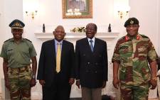 This screengrab from Zimbabwe Broadcasting Corporation (ZBC) taken on 16 November 2017, shows Zimbabwe President Robert Mugabe (2R) as he poses alongside Zimbabwe Defence Forces Commander General Constantino Chiwenga (R) and South African envoys at State House in Harare. Picture: AFP.